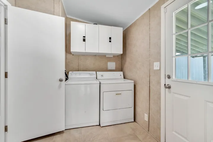 Laundry area featuring cabinet space, washer and clothes dryer, crown molding, and light tile patterned floors
