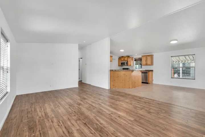 Unfurnished living room featuring light wood-style flooring and vaulted ceiling