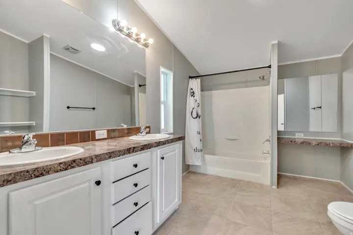 Full bath with double vanity, shower / bath combination with curtain, crown molding, and light tile patterned floors