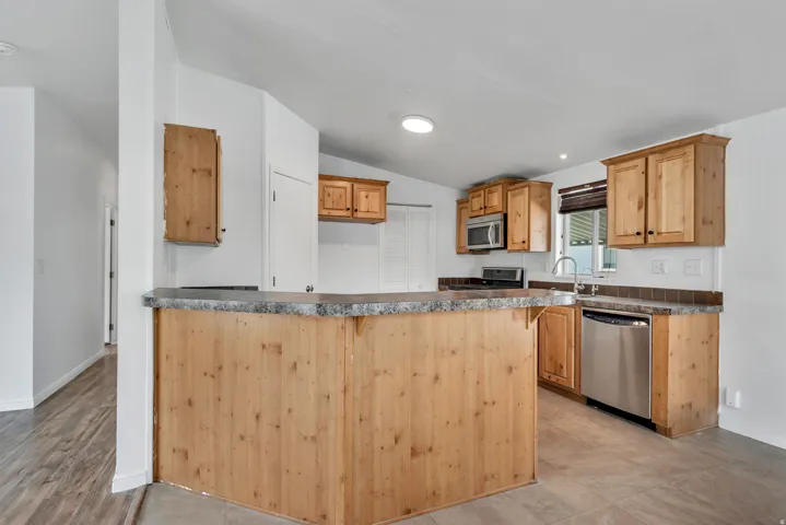 Kitchen with dark countertops, stainless steel appliances, a breakfast bar area, and vaulted ceiling