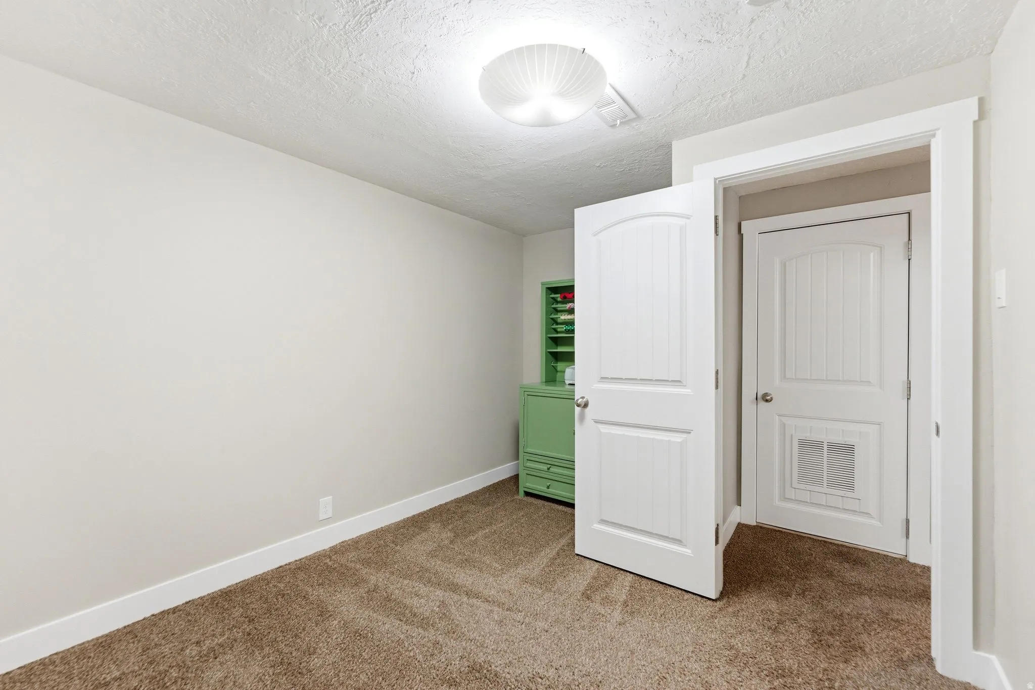 Unfurnished bedroom with light carpet and a textured ceiling