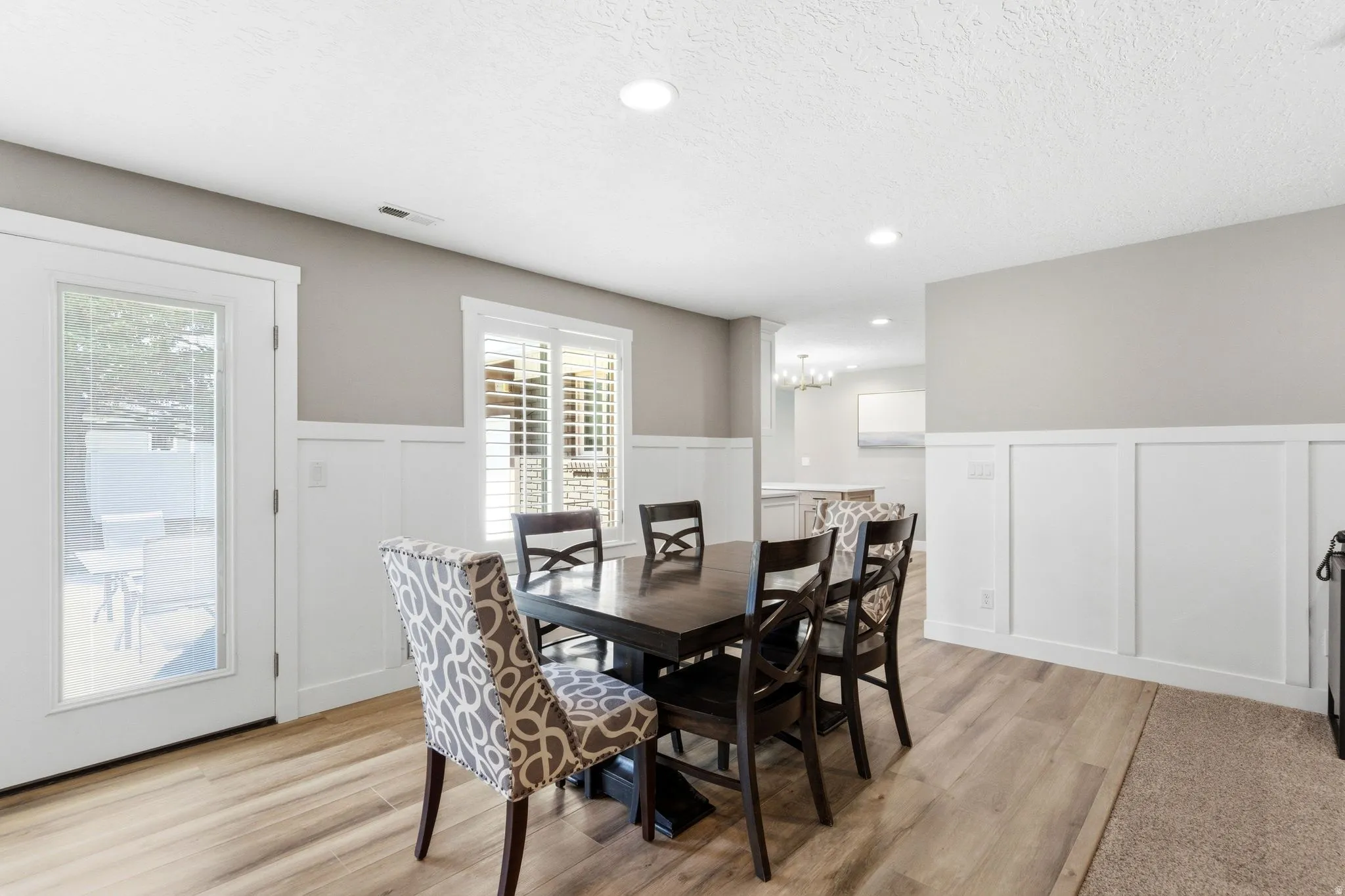 Dining area featuring a wainscoted wall, a decorative wall, recessed lighting, light wood-style flooring, and plenty of natural light
