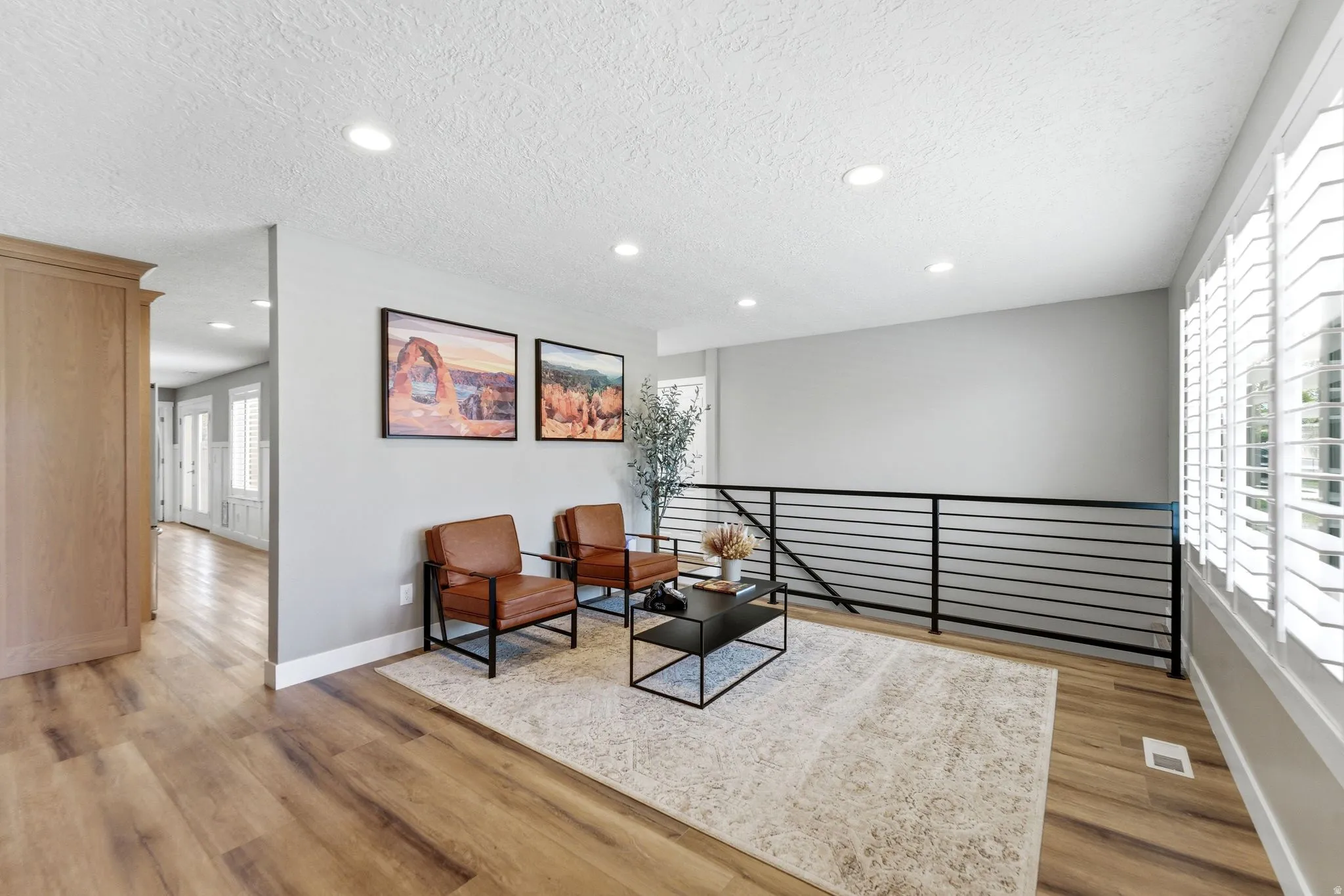 Living area with light wood-style flooring, recessed lighting, a textured ceiling, and an upstairs landing