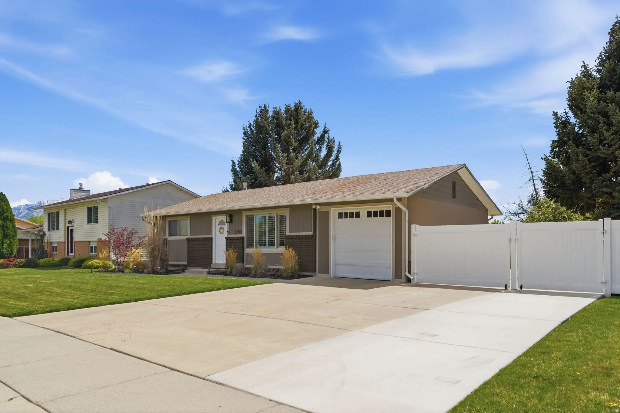 Ranch-style house featuring a gate, an attached garage, concrete driveway, a front lawn, and brick siding