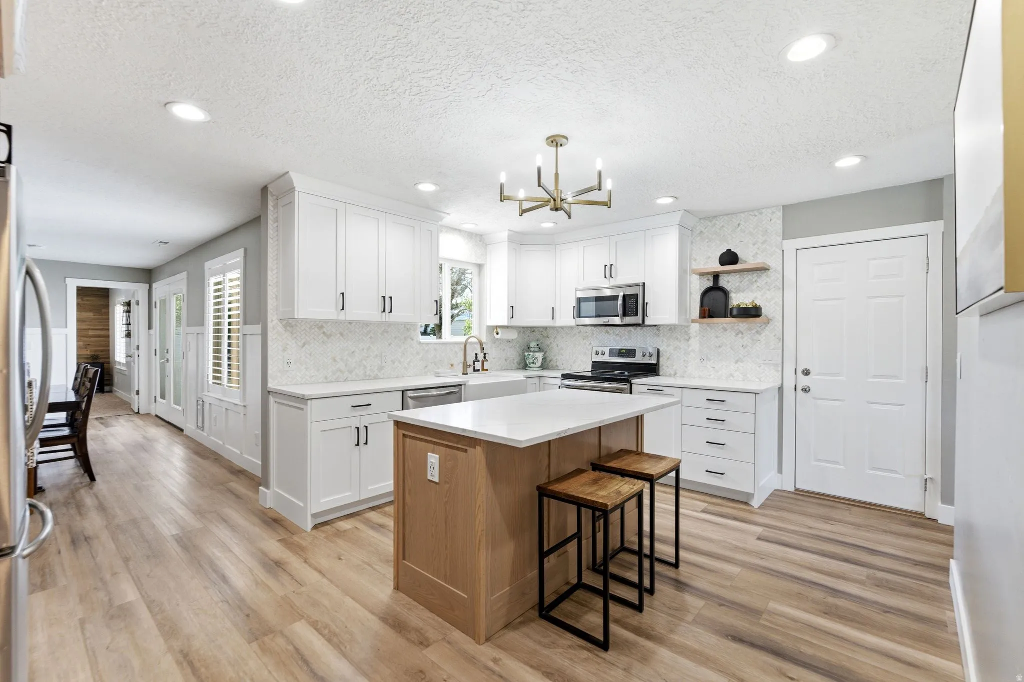 Kitchen featuring a kitchen island, open shelves, a breakfast bar area, light wood-style flooring, and stainless steel appliances