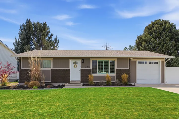 Single story home featuring a garage, a front lawn, and brick siding