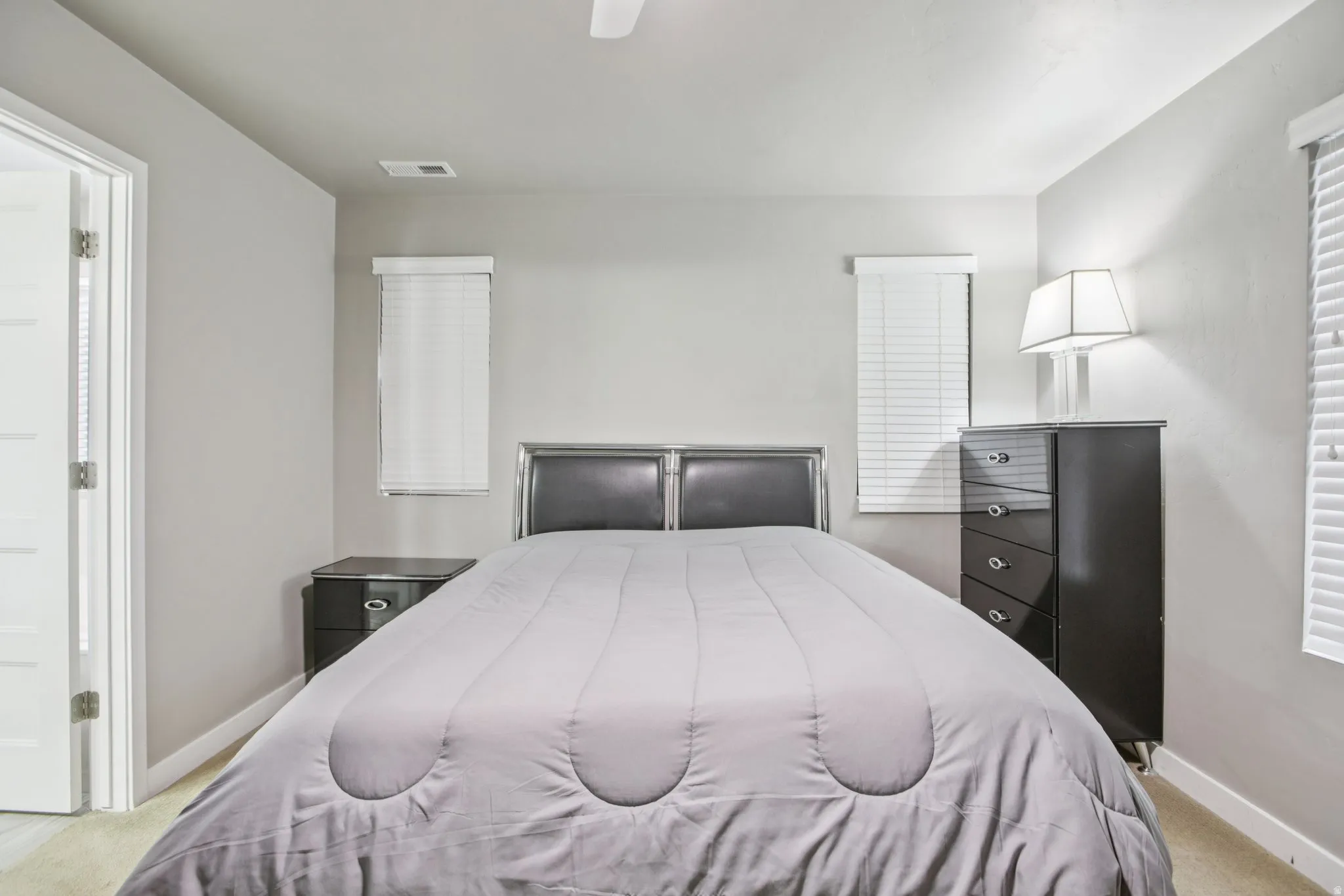 Bedroom with light colored carpet, a ceiling fan, and ensuite bathroom