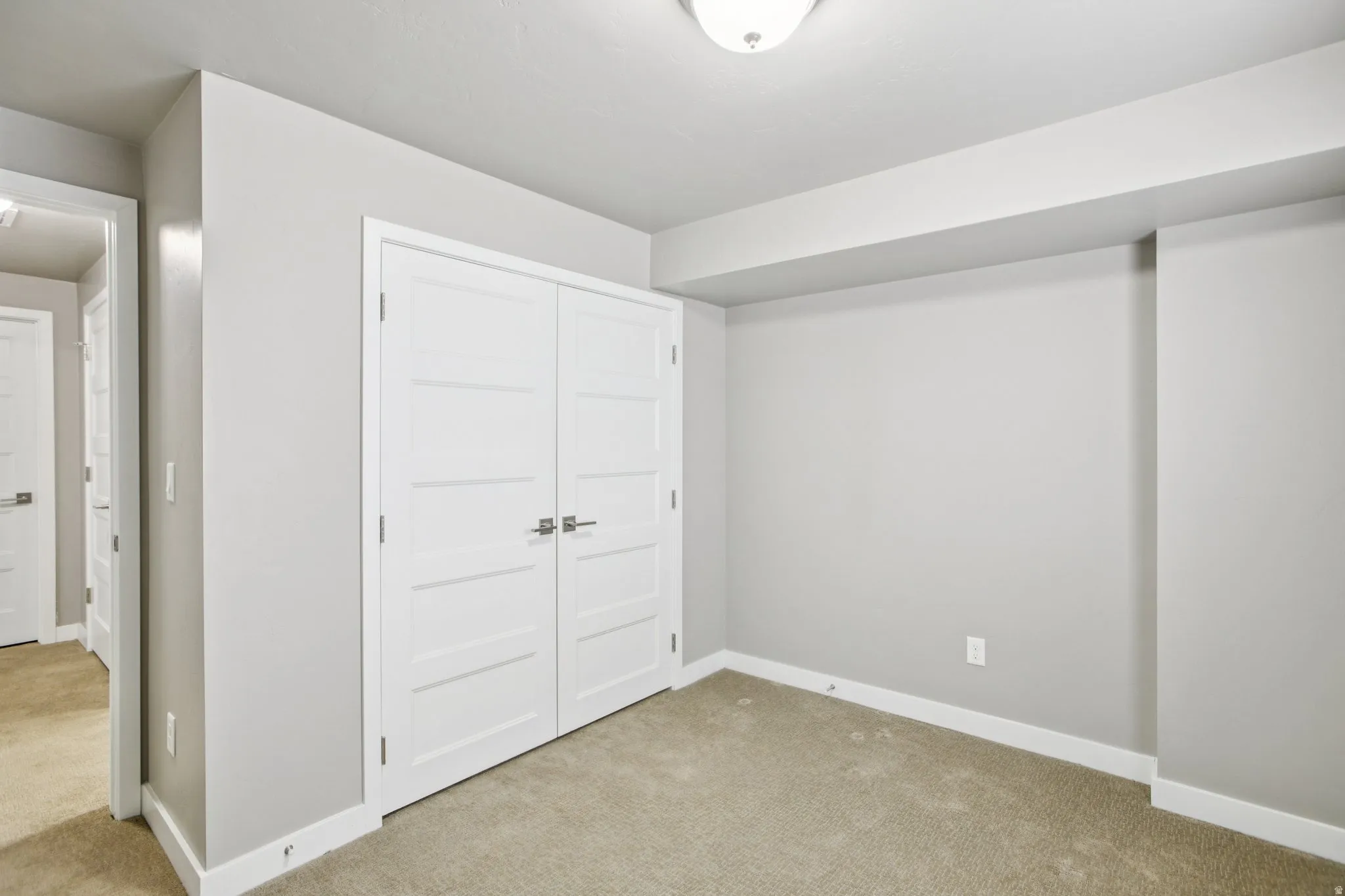 Unfurnished bedroom with light colored carpet and a closet