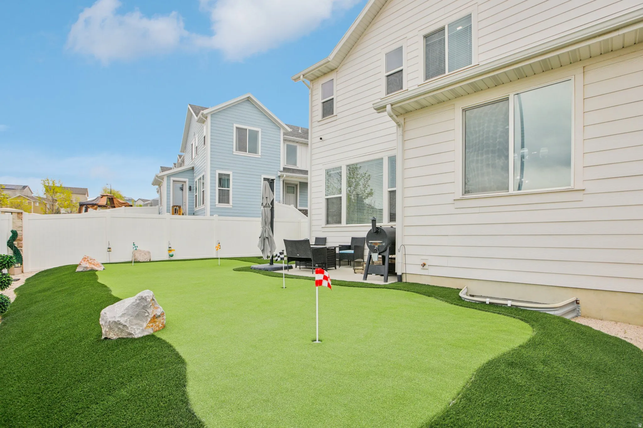 Fenced backyard with a patio area and a putting green