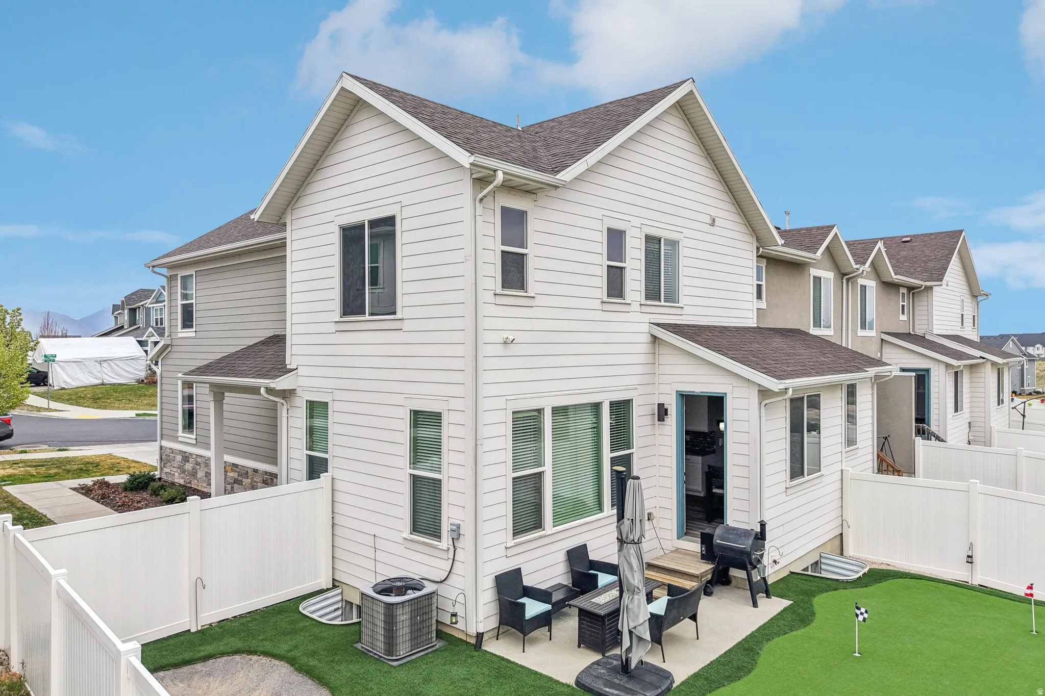 Back of property featuring roof with shingles, an outdoor living space, a fenced backyard, and an area to practice putting