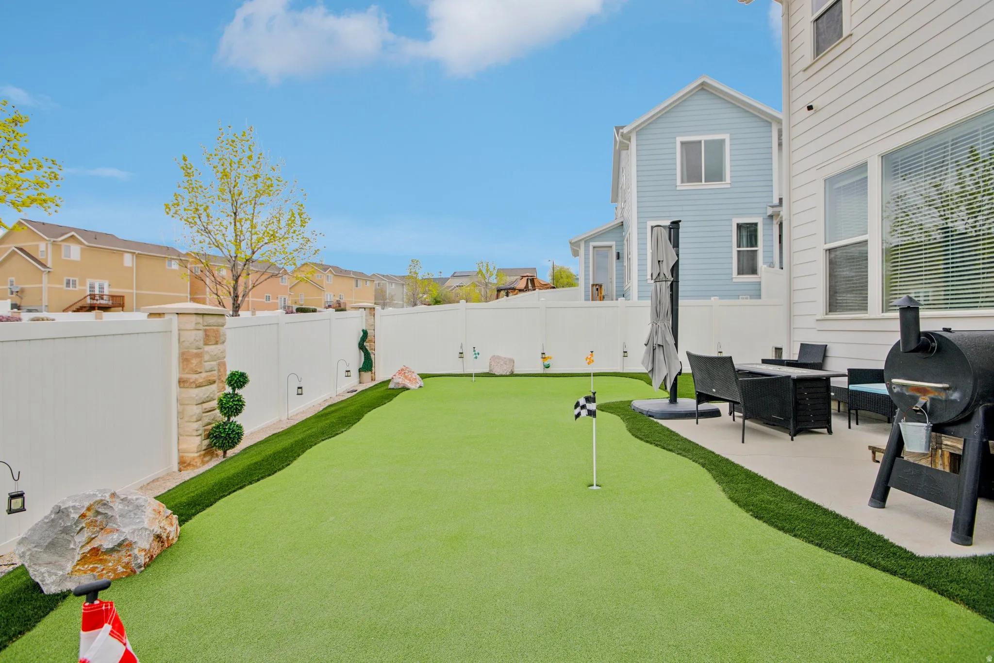 Fenced backyard featuring a residential view, a putting green, and a patio area