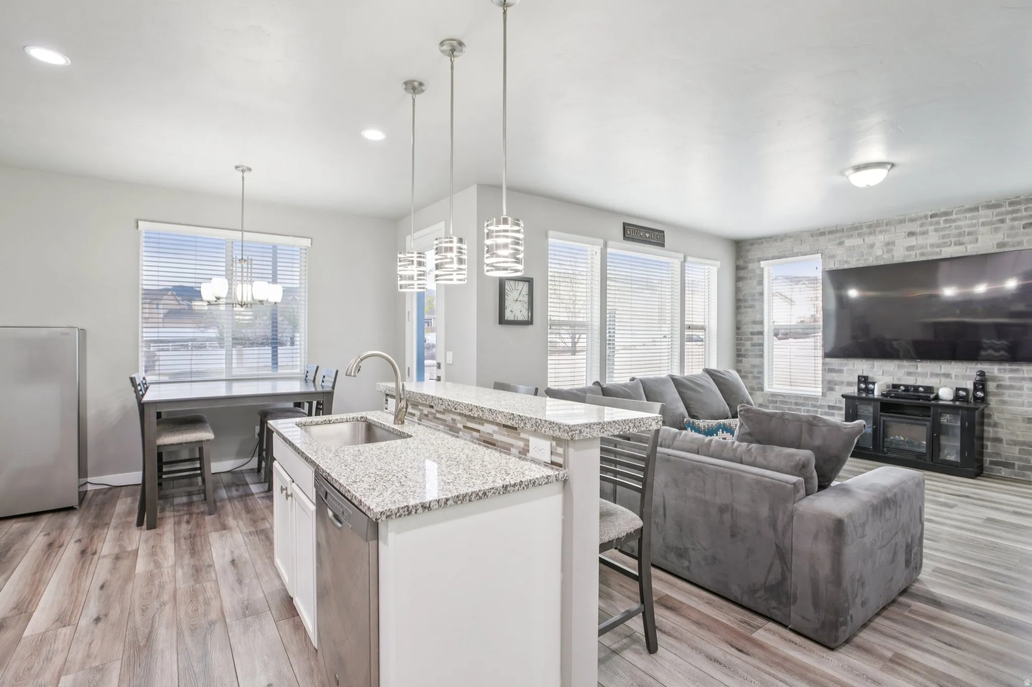 Kitchen featuring a breakfast bar area, light stone countertops, brick wall, light wood-style floors, and white cabinetry