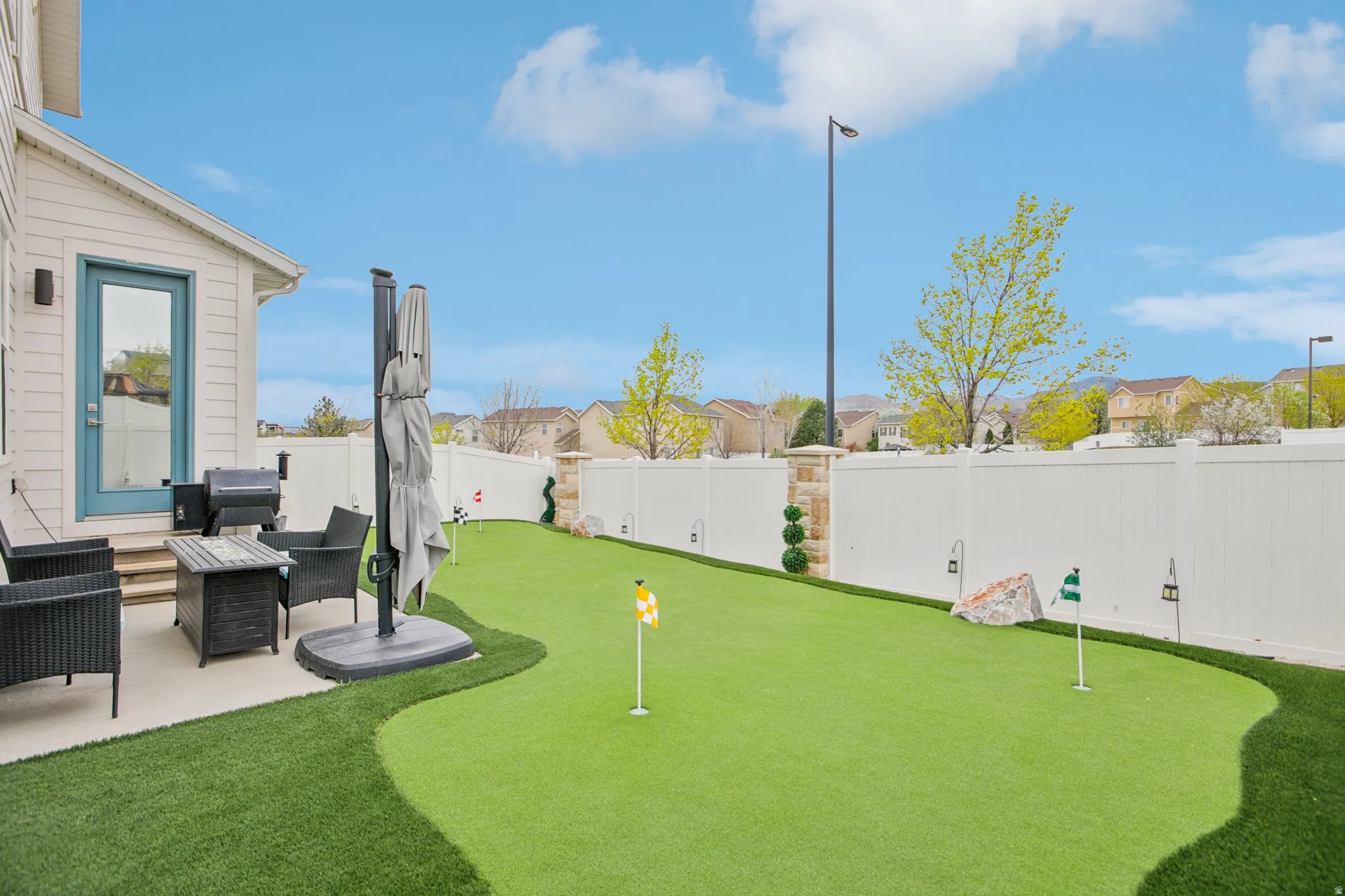 Fenced backyard with a residential view, a putting area, a patio, and outdoor lounge area