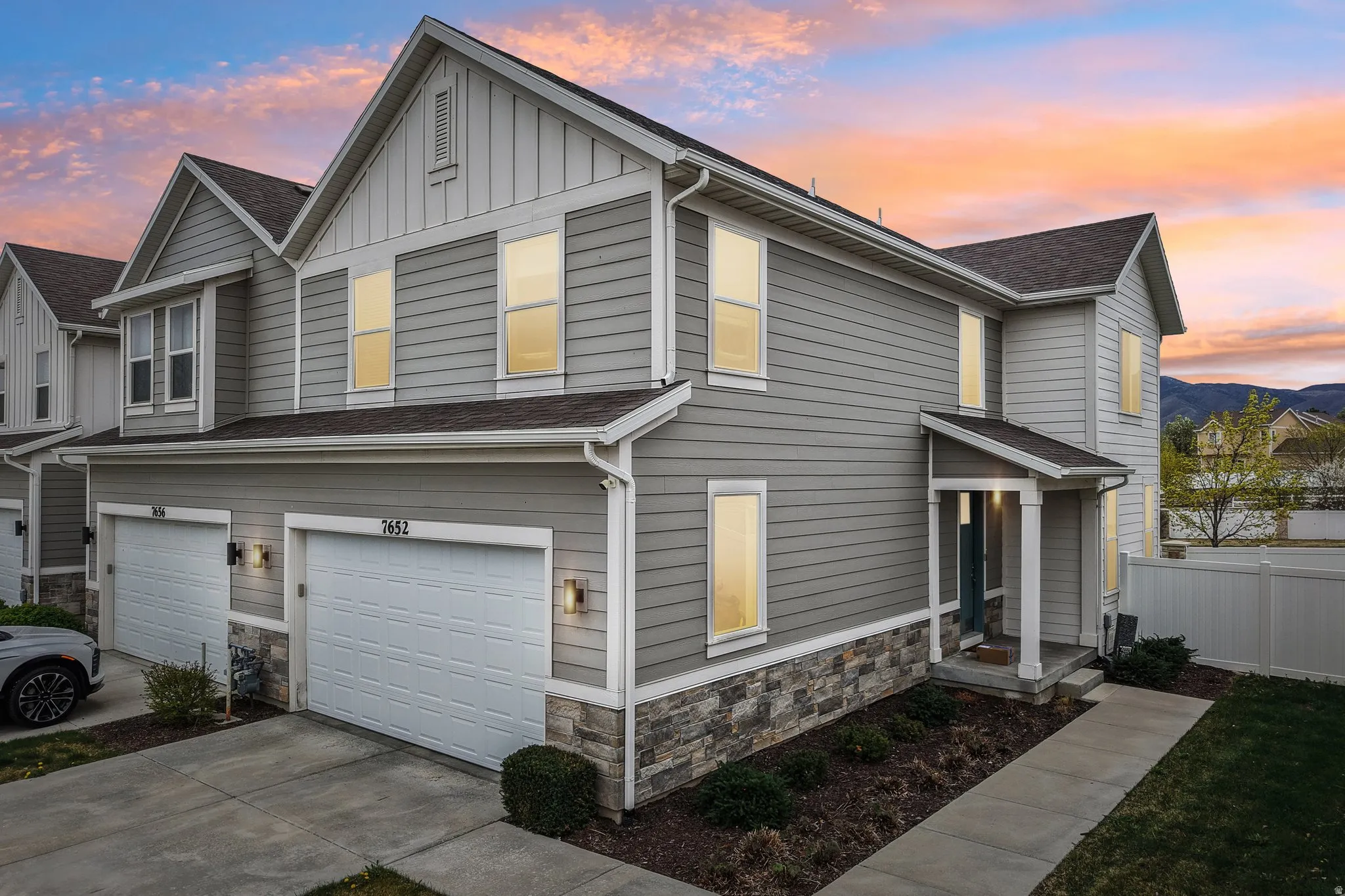 View of front facade featuring stone siding, board and batten siding, an attached garage, driveway, and roof with shingles