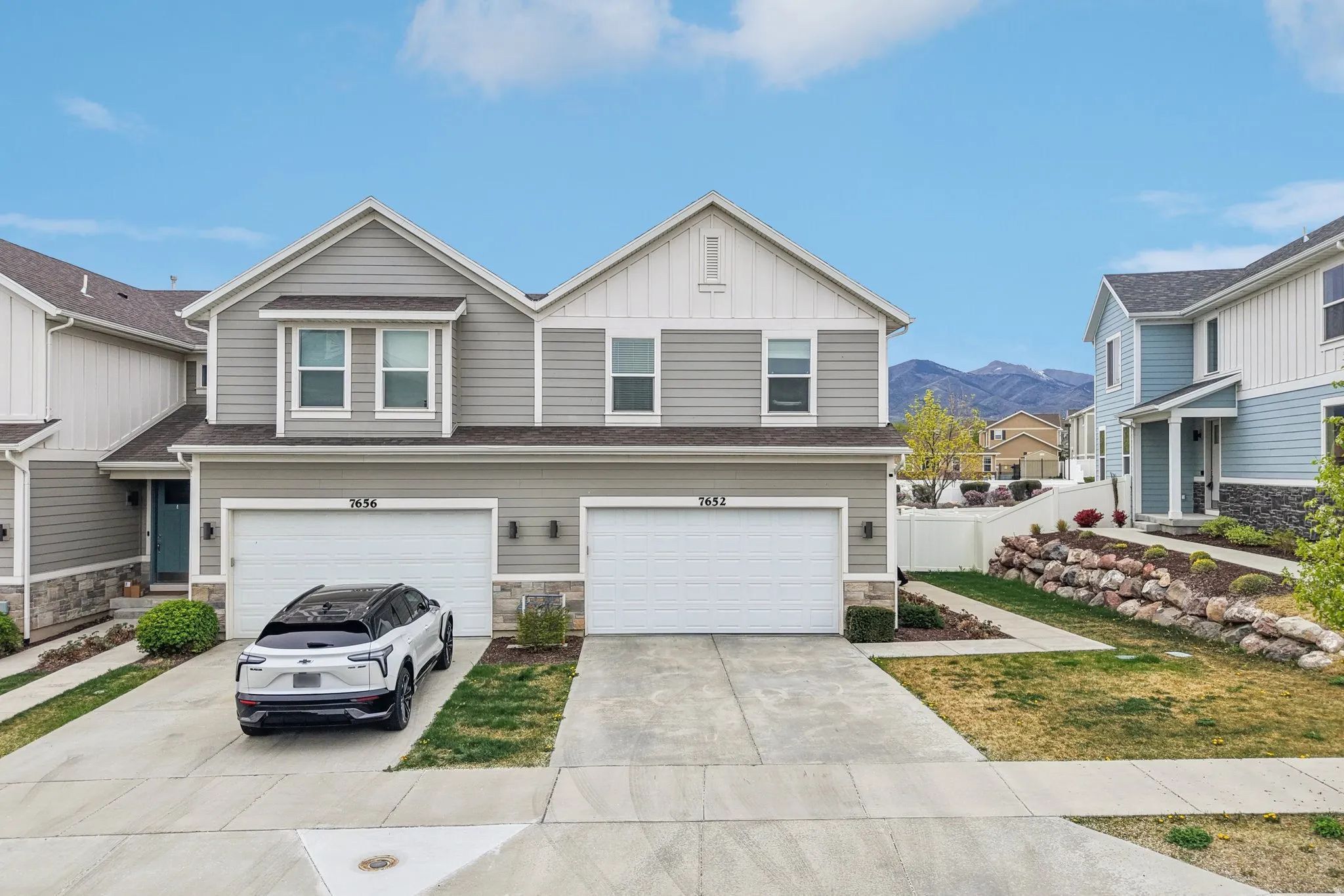 View of front of property featuring stone siding, board and batten siding, driveway, and an attached garage