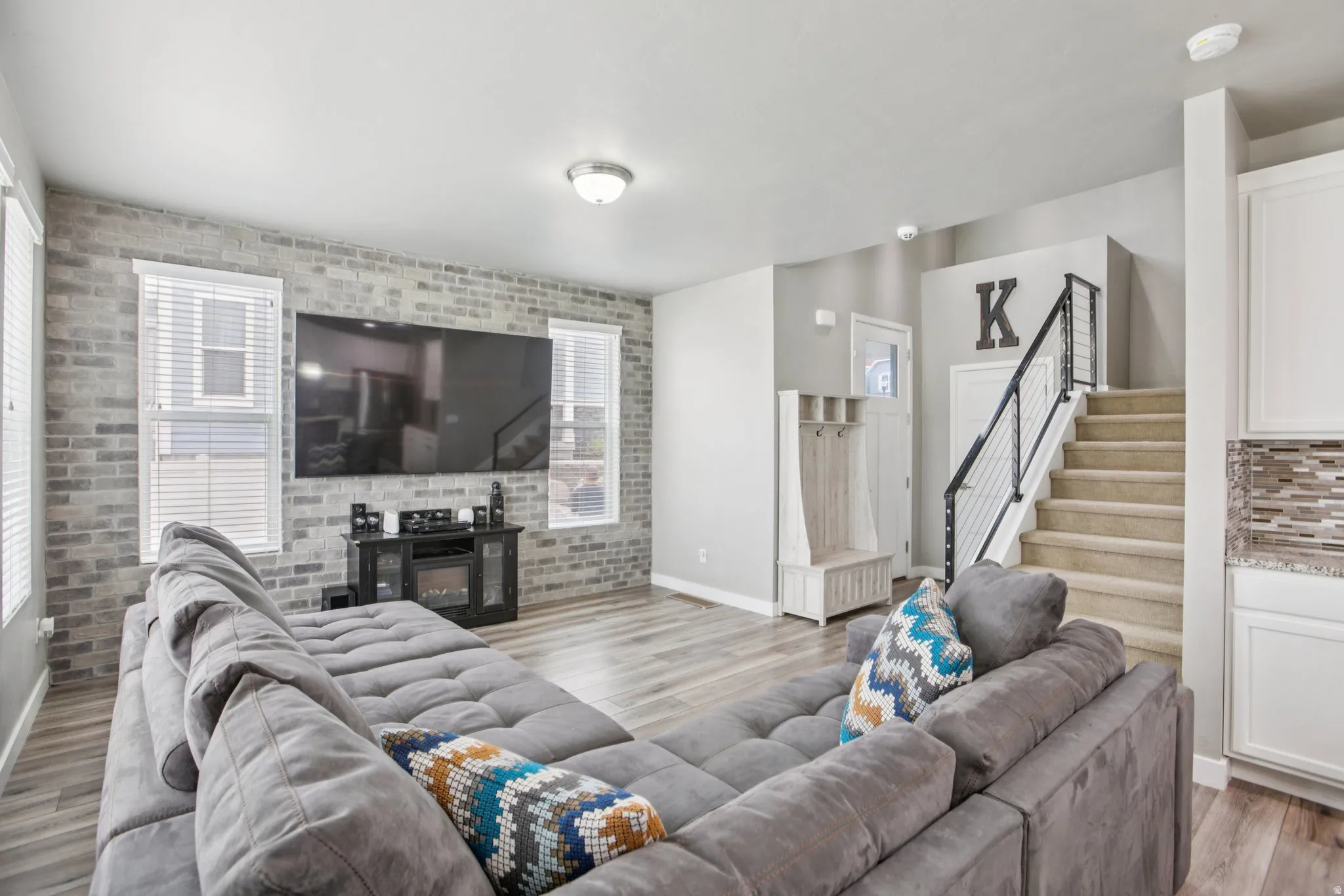 Living area featuring brick wall, light wood-style floors, and a glass covered fireplace
