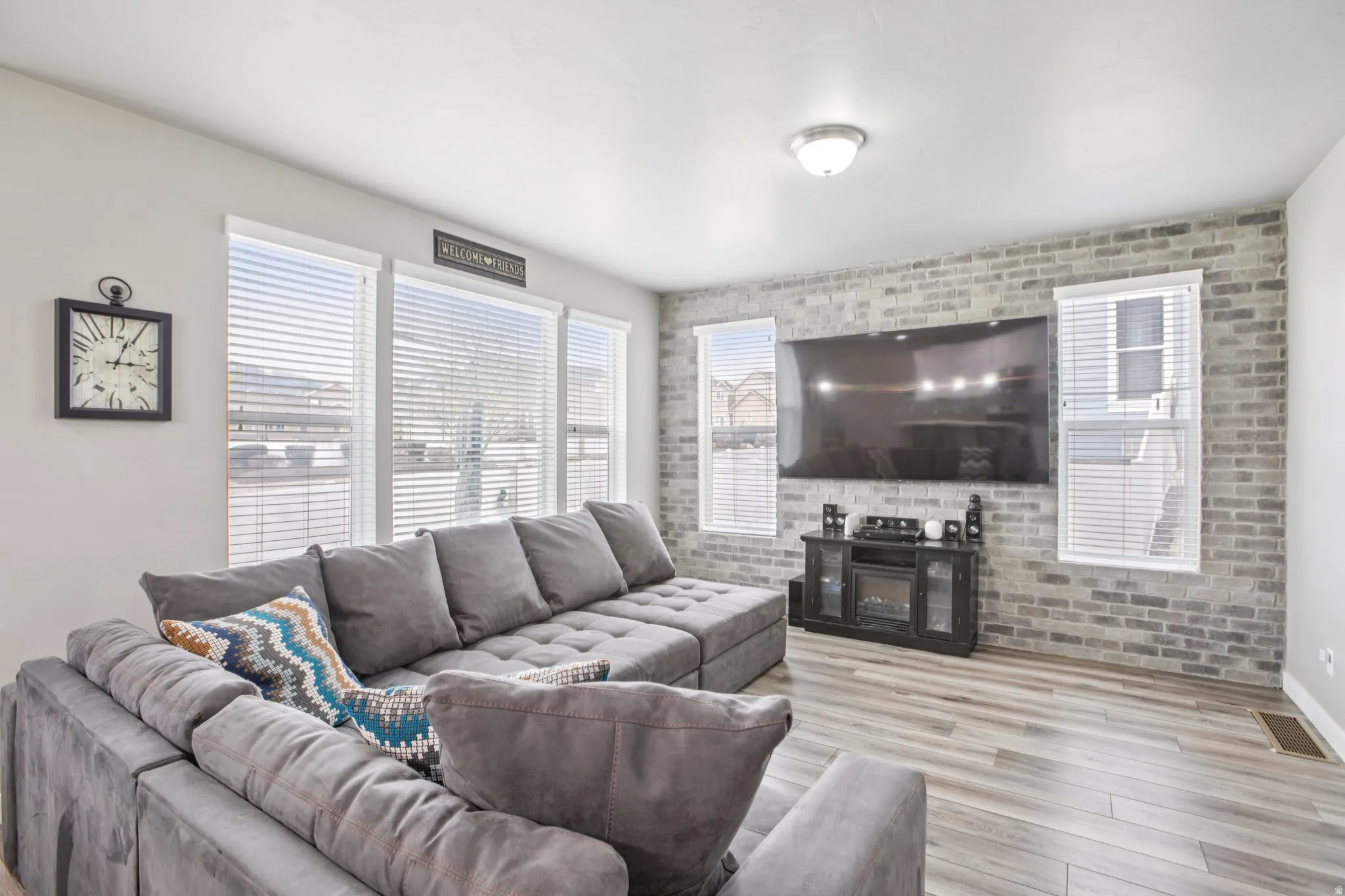 Living room featuring brick wall, light wood-style floors, and healthy amount of natural light