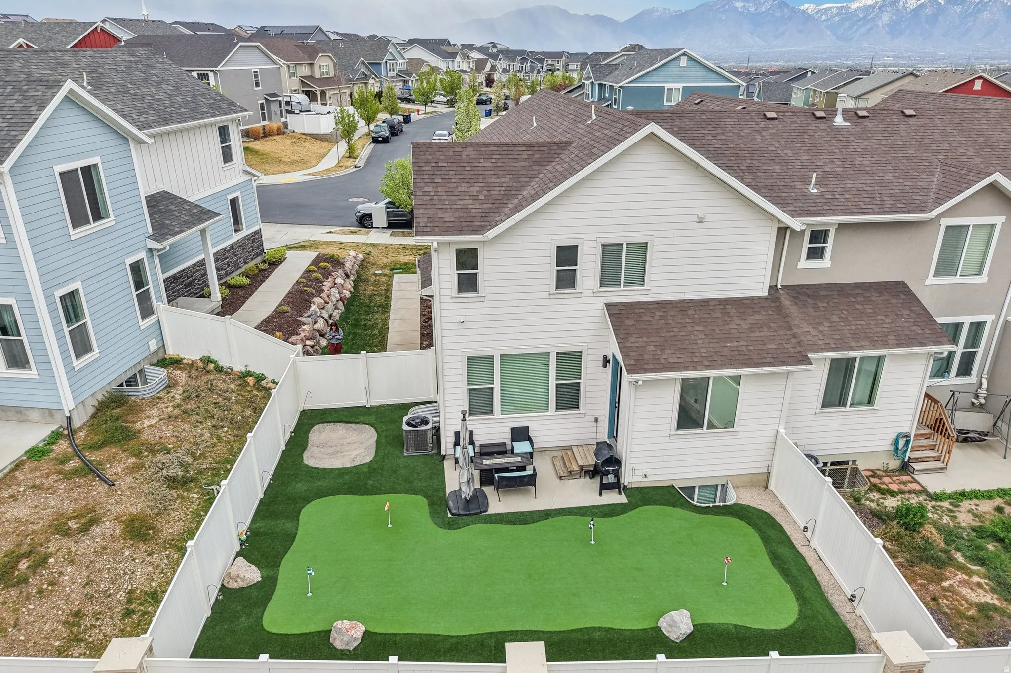 Back of property featuring a patio, a fenced backyard, a shingled roof, a putting green, and a residential view