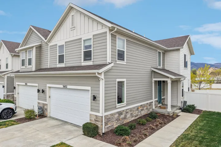 Craftsman-style house with stone siding, board and batten siding, an attached garage, roof with shingles, and concrete driveway