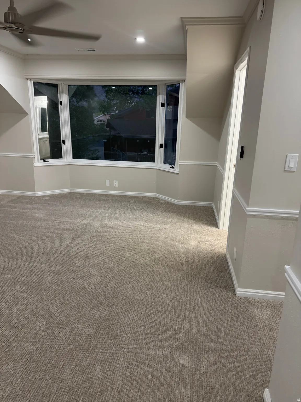 Empty room with carpet flooring and a ceiling fan