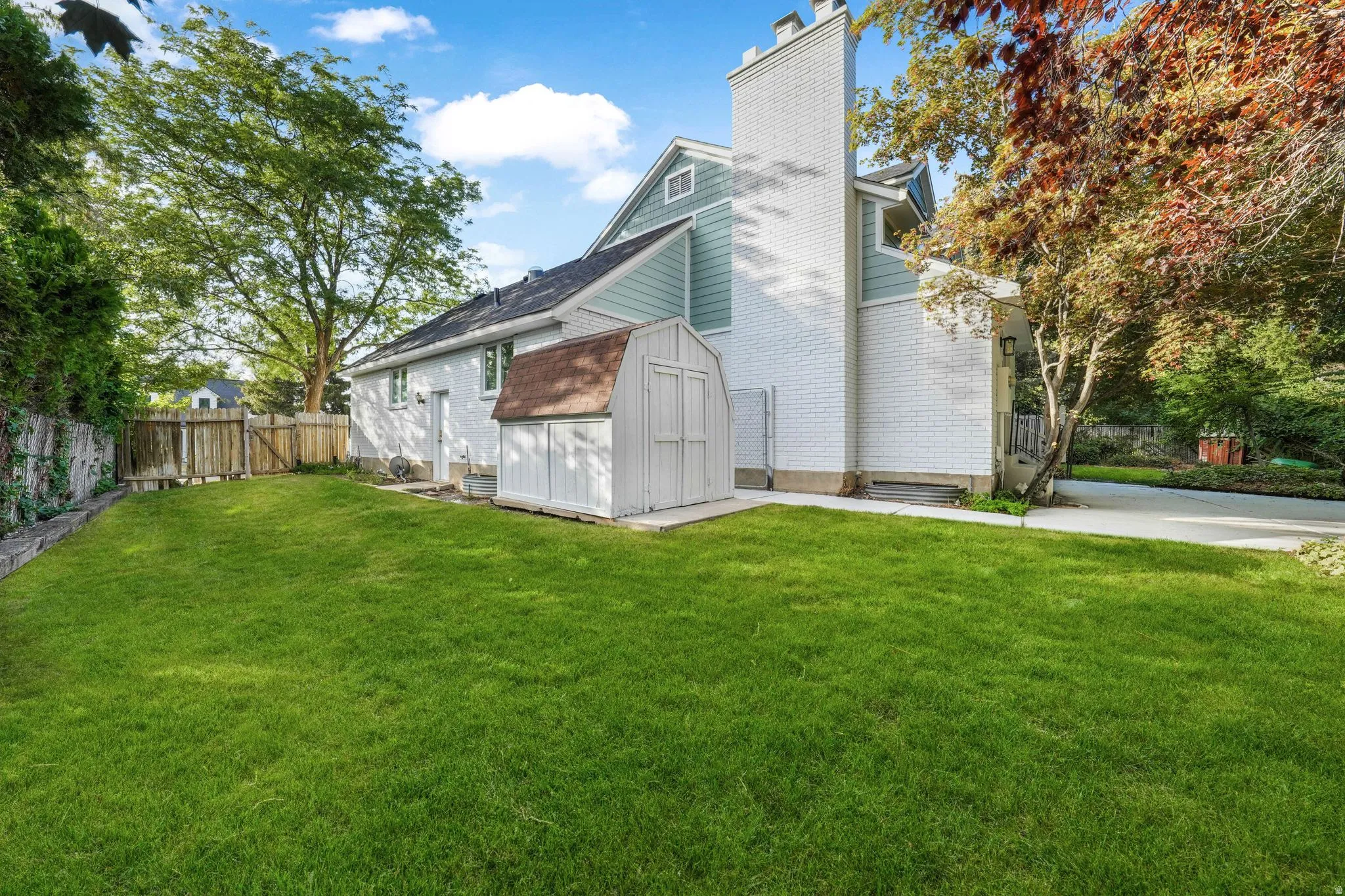 View of home's exterior featuring a chimney, a shed, roof with shingles, and brick siding