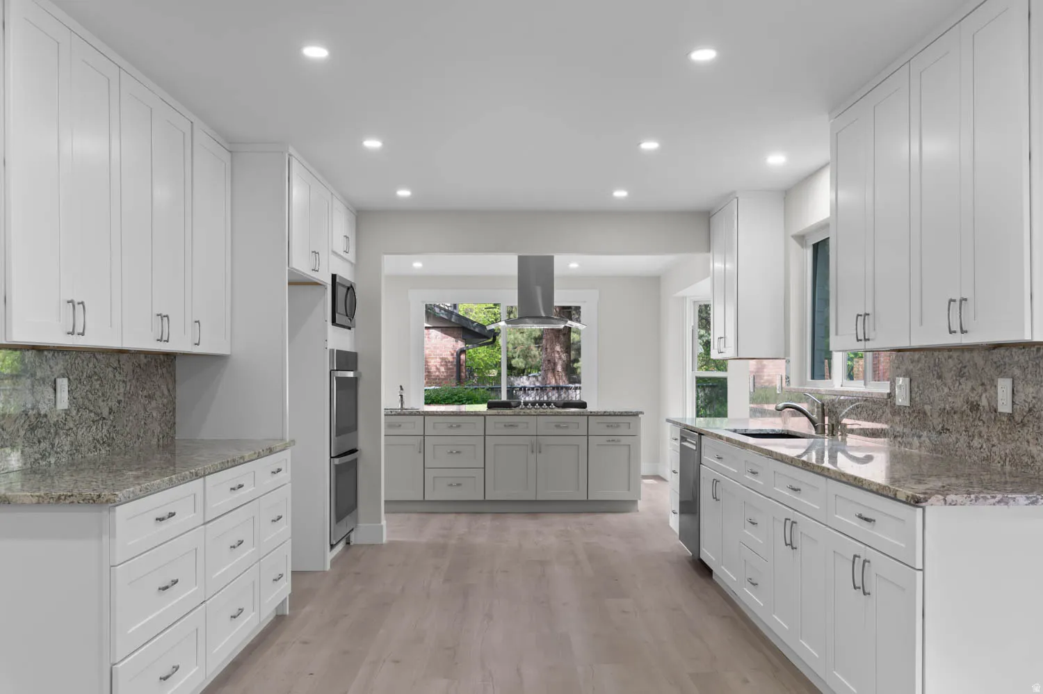 Kitchen with tasteful backsplash, dark stone counters, recessed lighting, white cabinetry, and light wood-style flooring