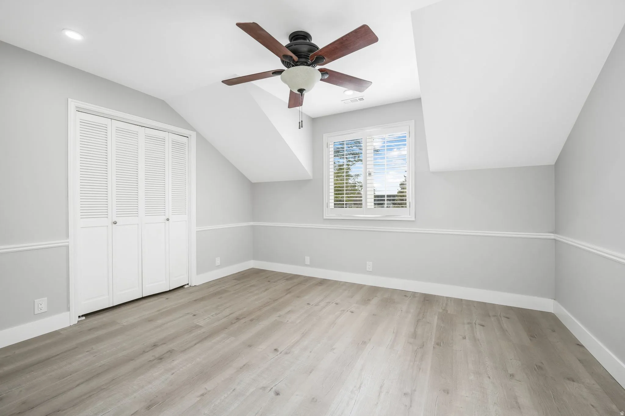 Additional living space with ceiling fan, lofted ceiling, and light wood-type flooring