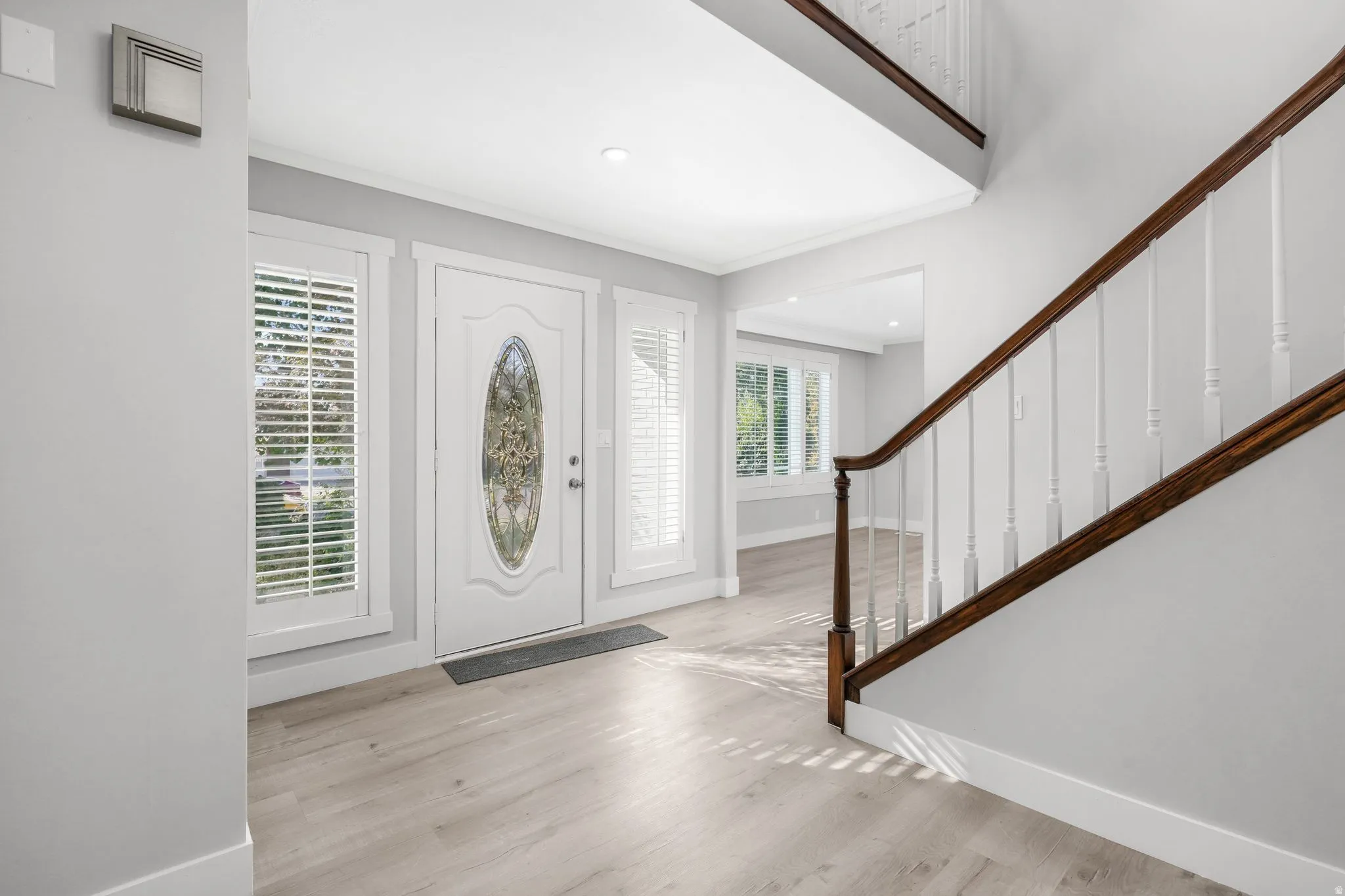 Foyer featuring light wood-style flooring, ornamental molding, and recessed lighting