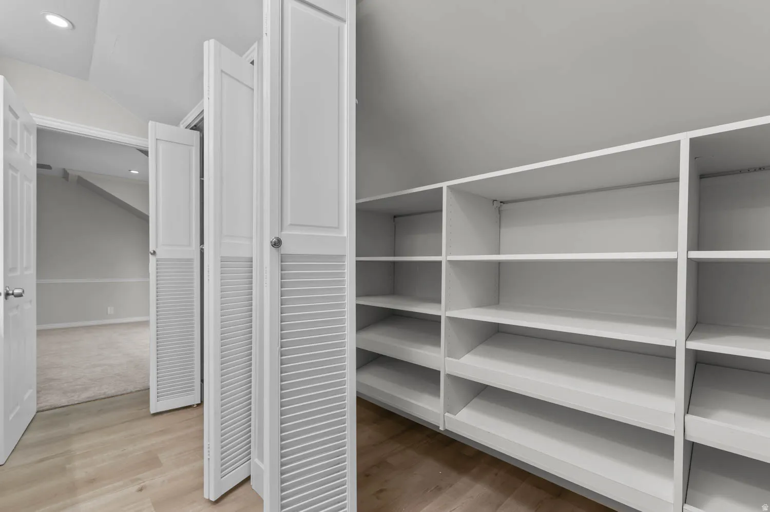 Walk in closet featuring light wood-style flooring and vaulted ceiling