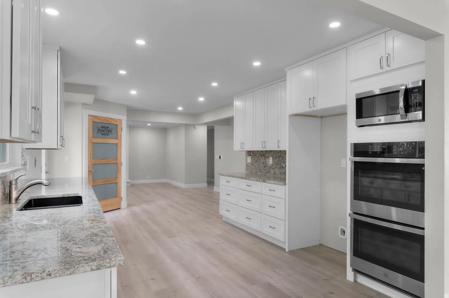 Kitchen featuring stainless steel appliances, white cabinetry, light stone counters, and recessed lighting