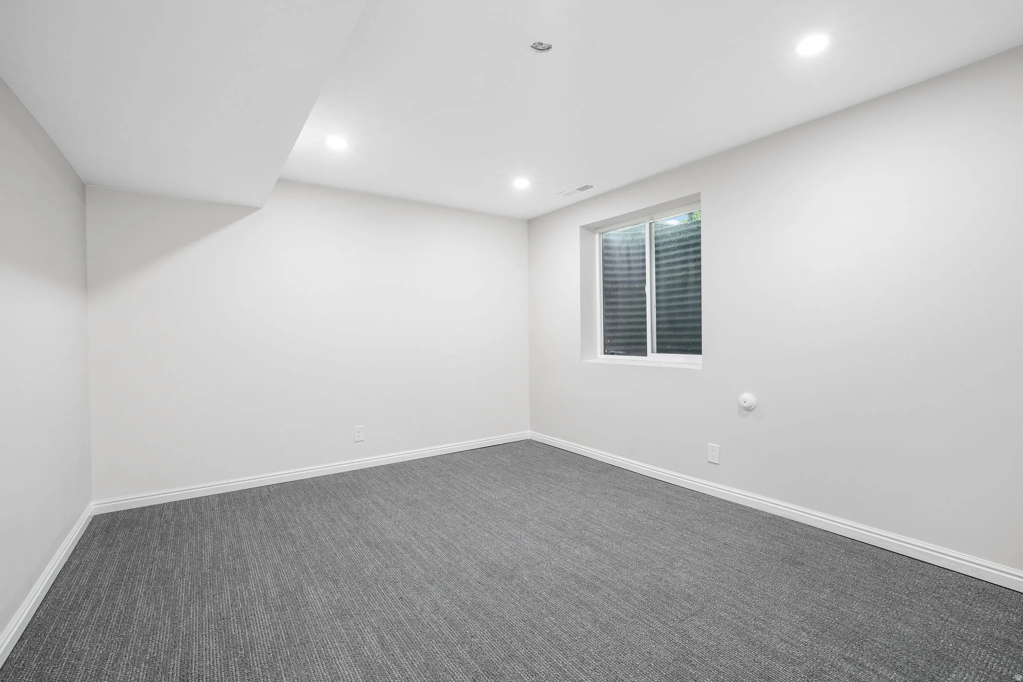 Empty room with dark carpet and recessed lighting