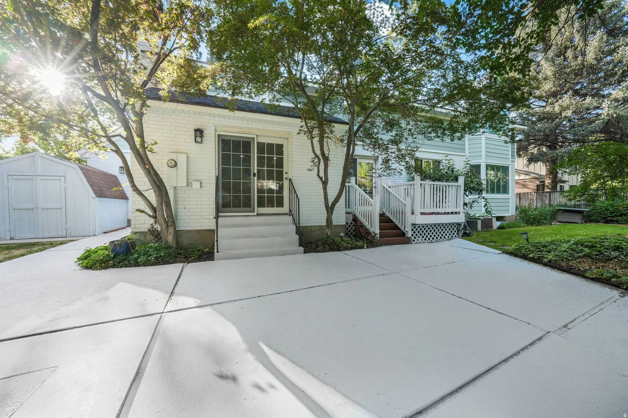 View of front of home with a patio, a storage shed, and brick siding