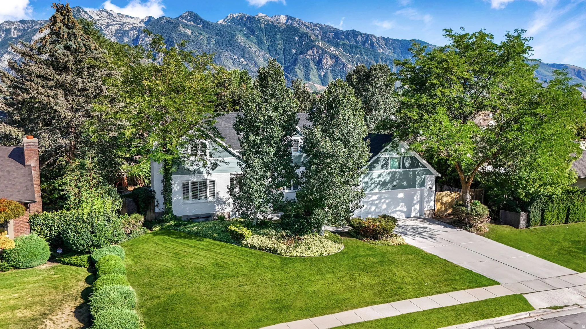 View of front of property featuring a mountain view, driveway, and a front lawn