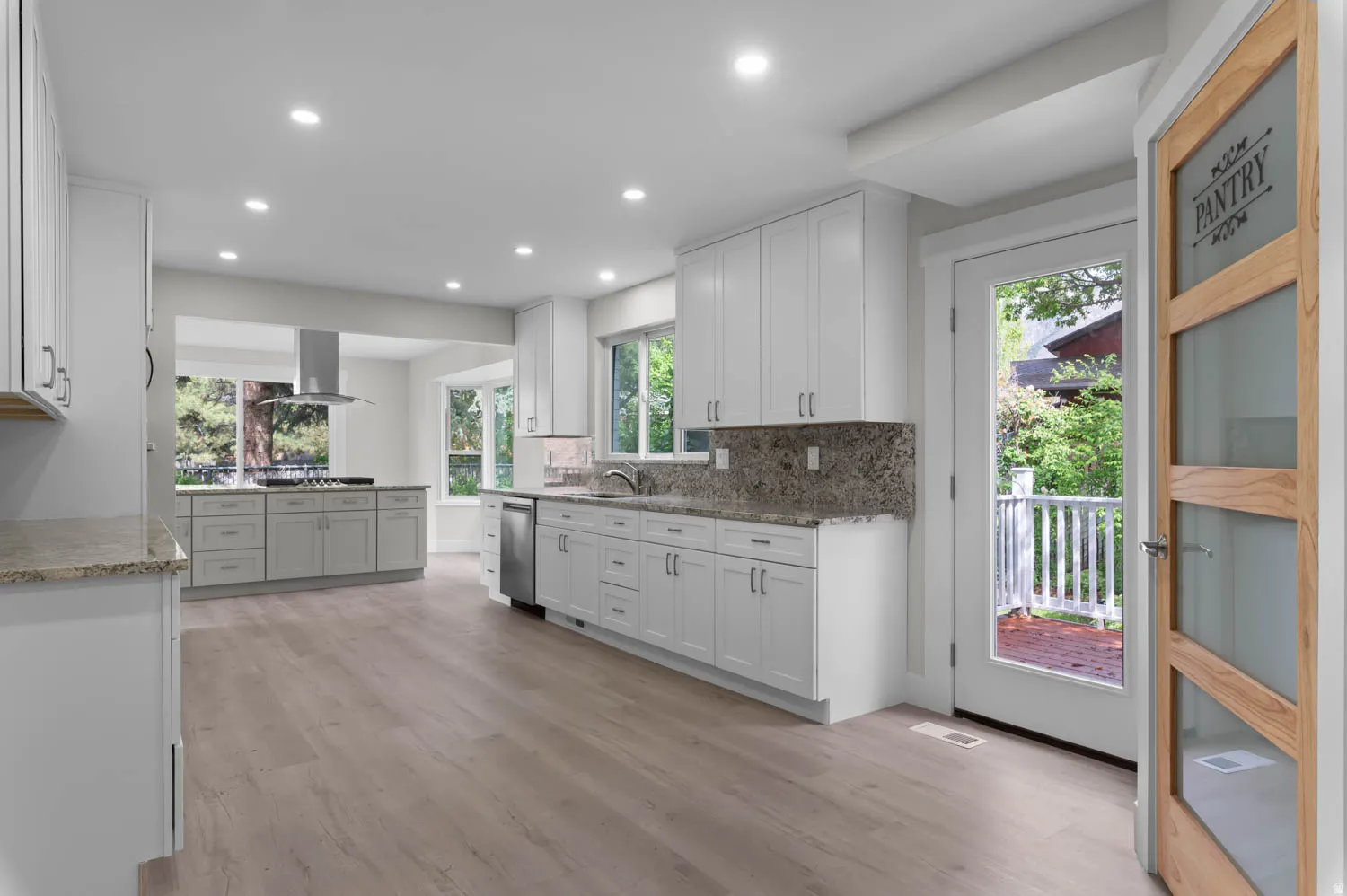 Kitchen featuring light stone counters, white cabinets, recessed lighting, and healthy amount of natural light