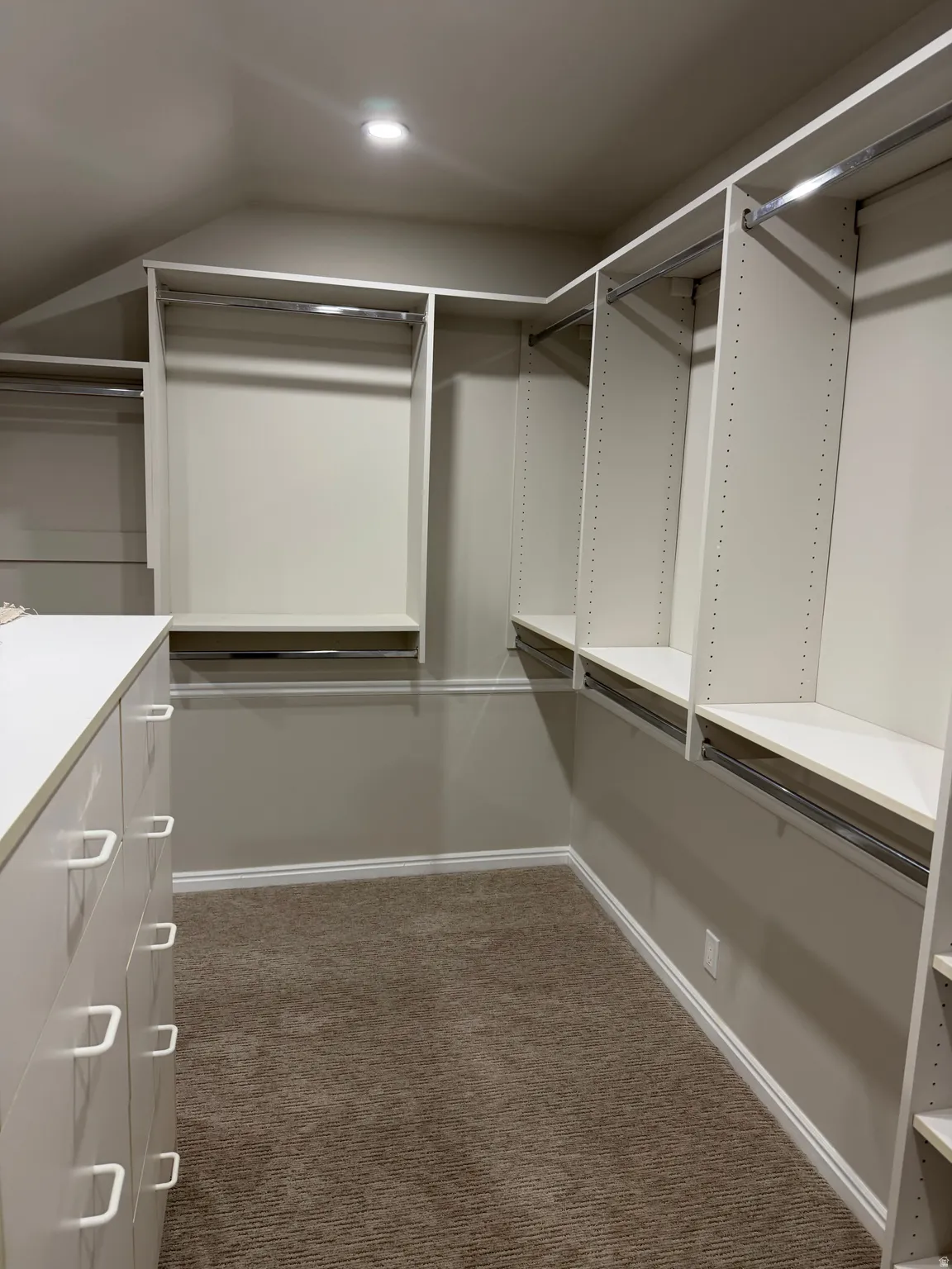 Walk in closet featuring dark colored carpet and lofted ceiling
