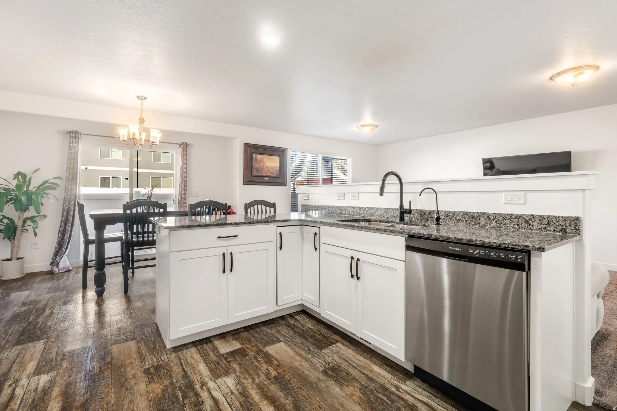 Kitchen featuring dishwasher, white cabinets, dark stone countertops, and dark wood-style flooring
