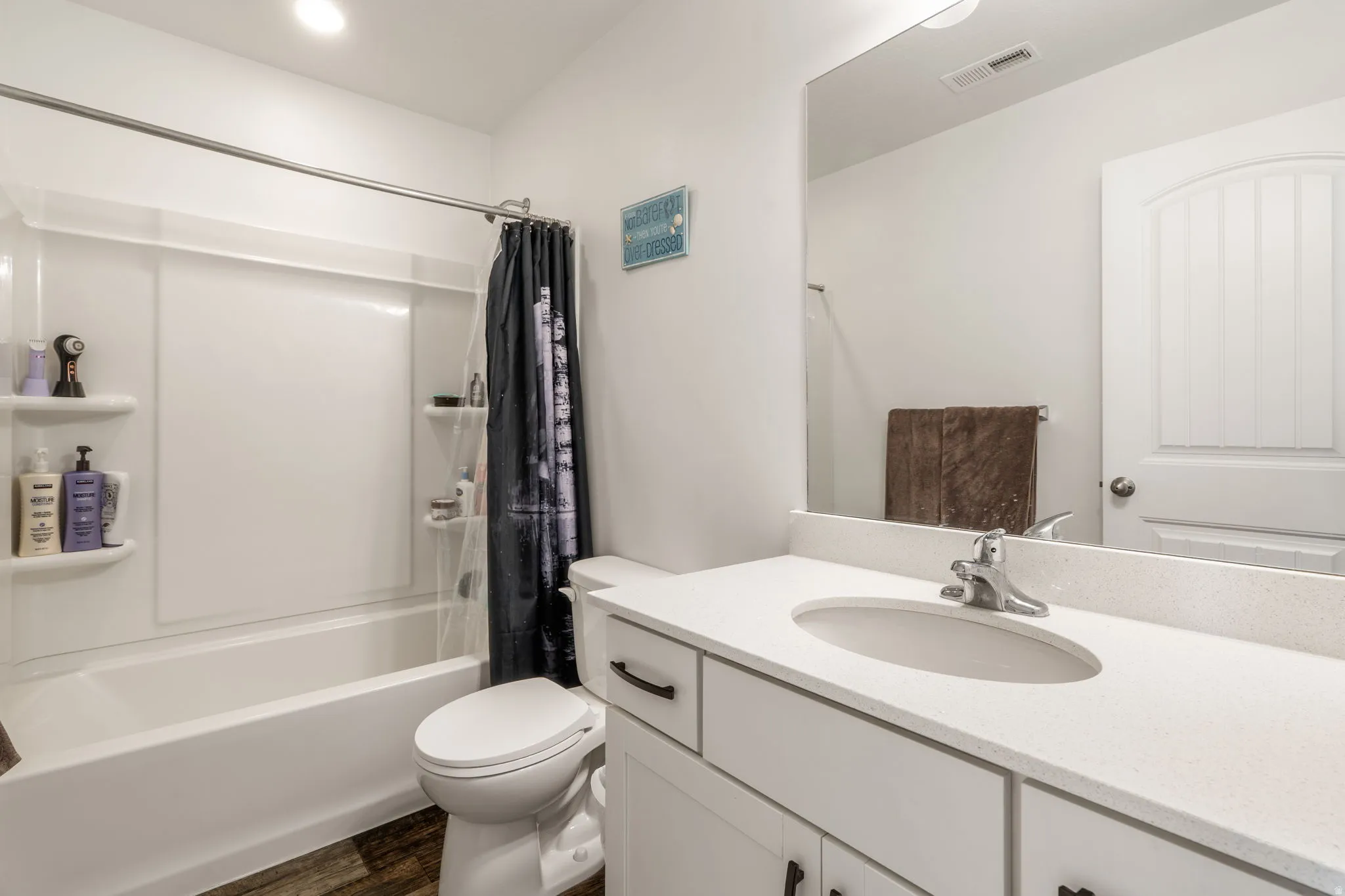 Bathroom with vanity, shower / bath combination with curtain, and dark wood-style flooring