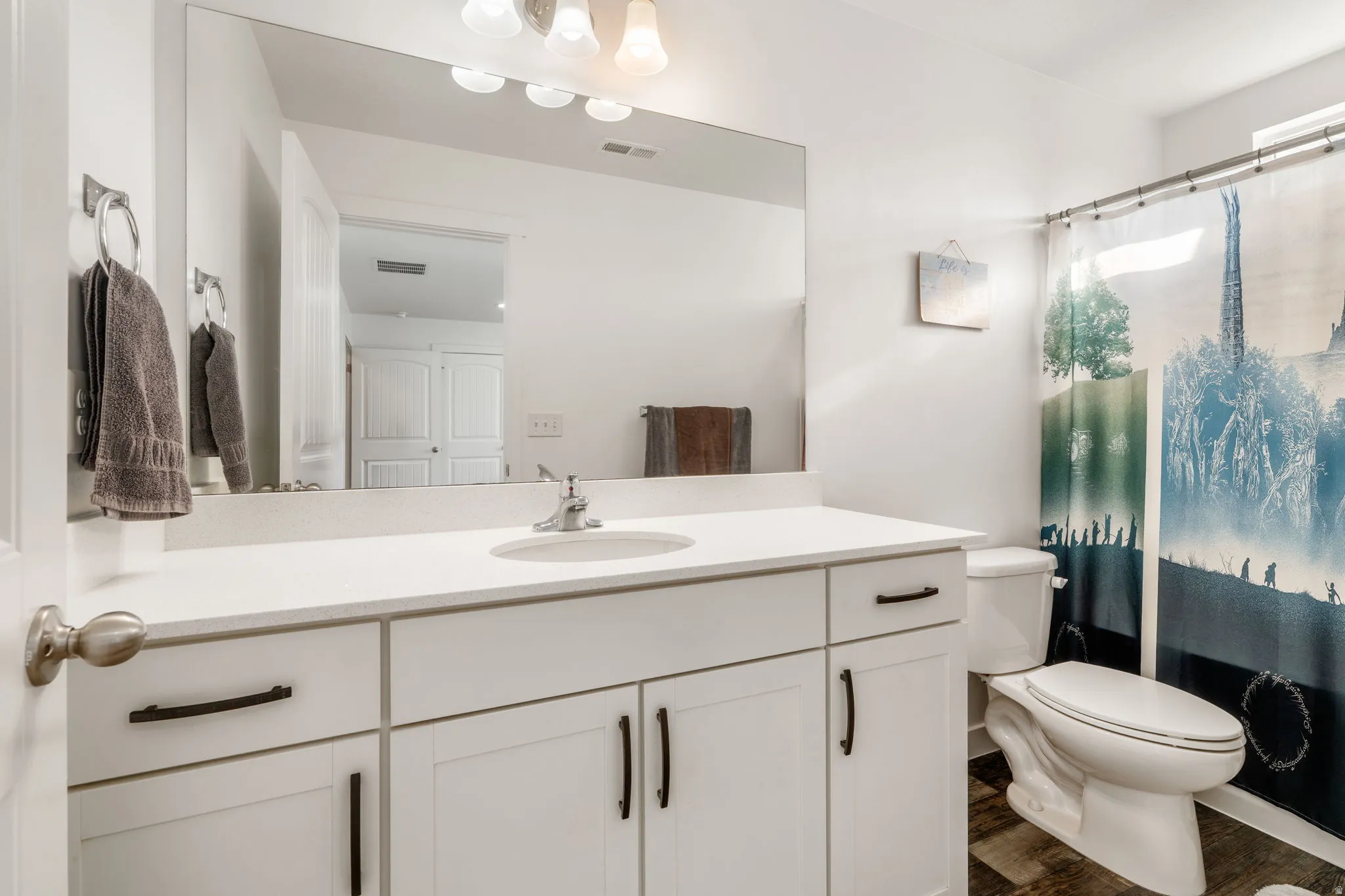 Full bath with curtained shower, vanity, and dark wood finished floors