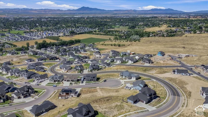 Newly developed residential area with numerous single-family homes, curvilinear street design, and distant mountain backdrop