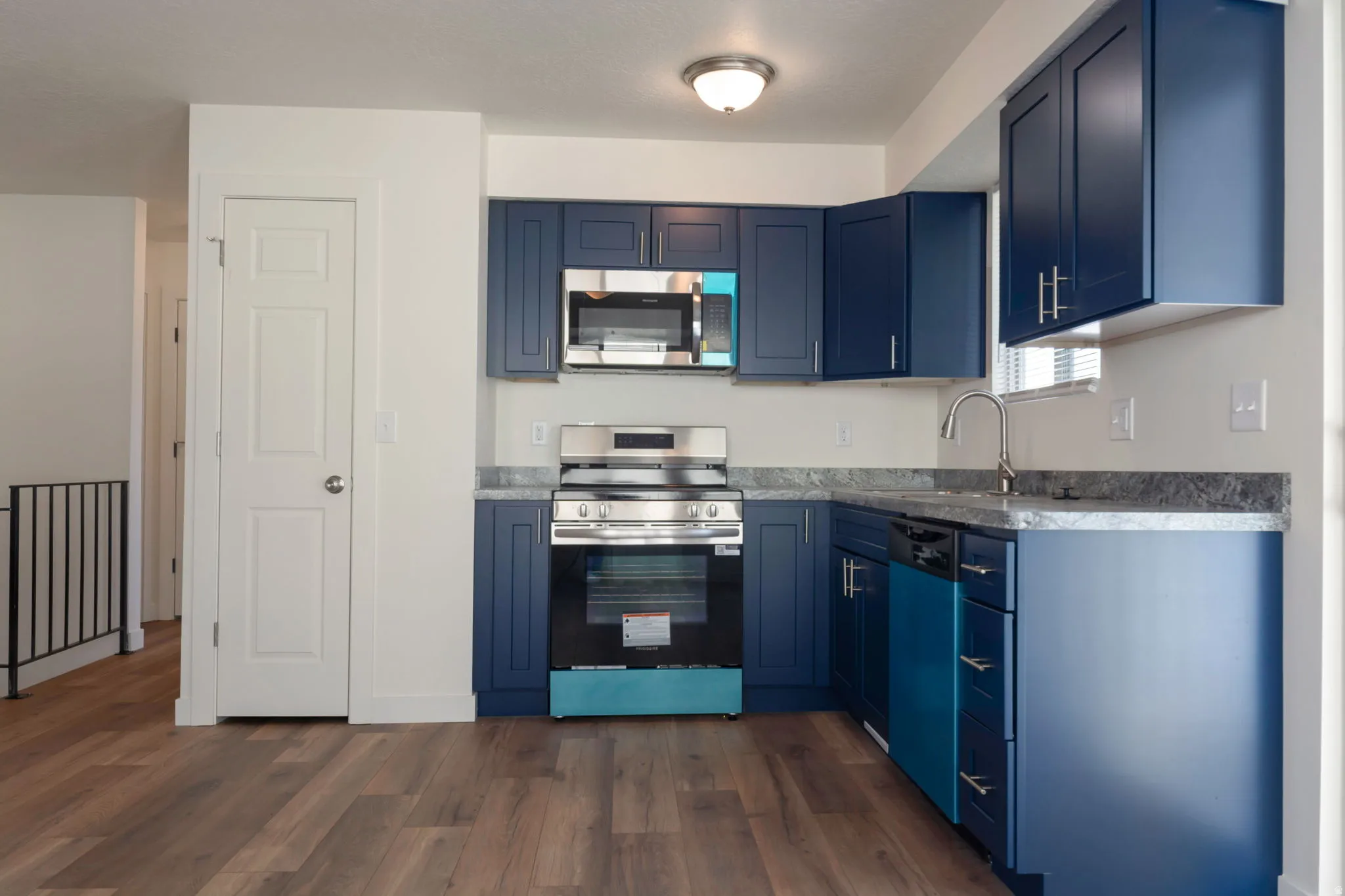 Kitchen featuring stainless steel appliances, blue cabinets, and dark wood-style flooring