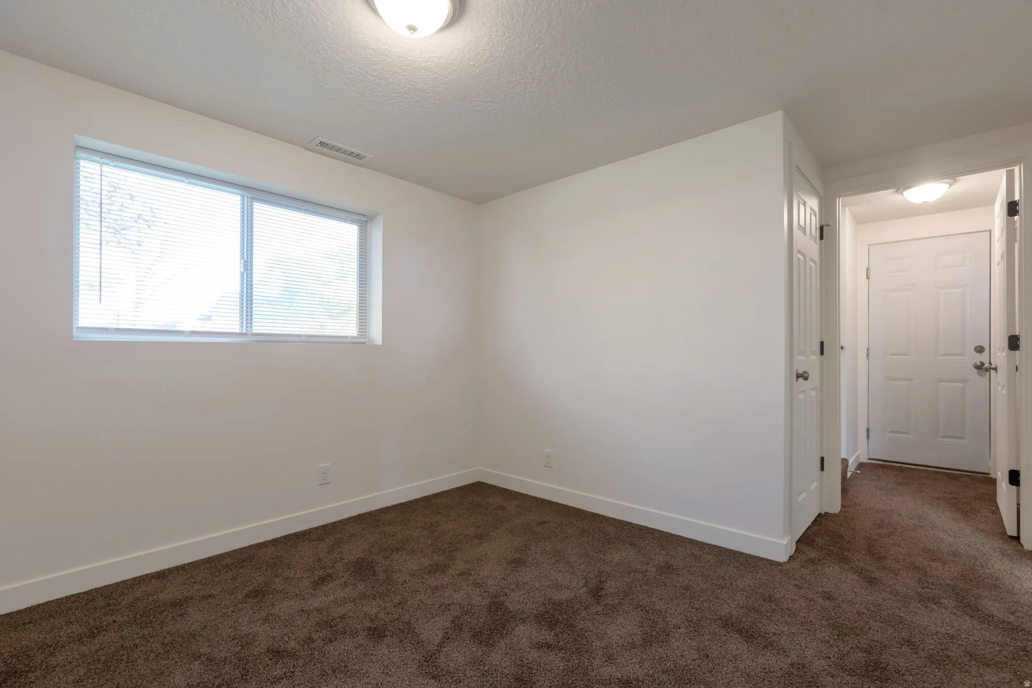 Empty room featuring dark carpet and a textured ceiling