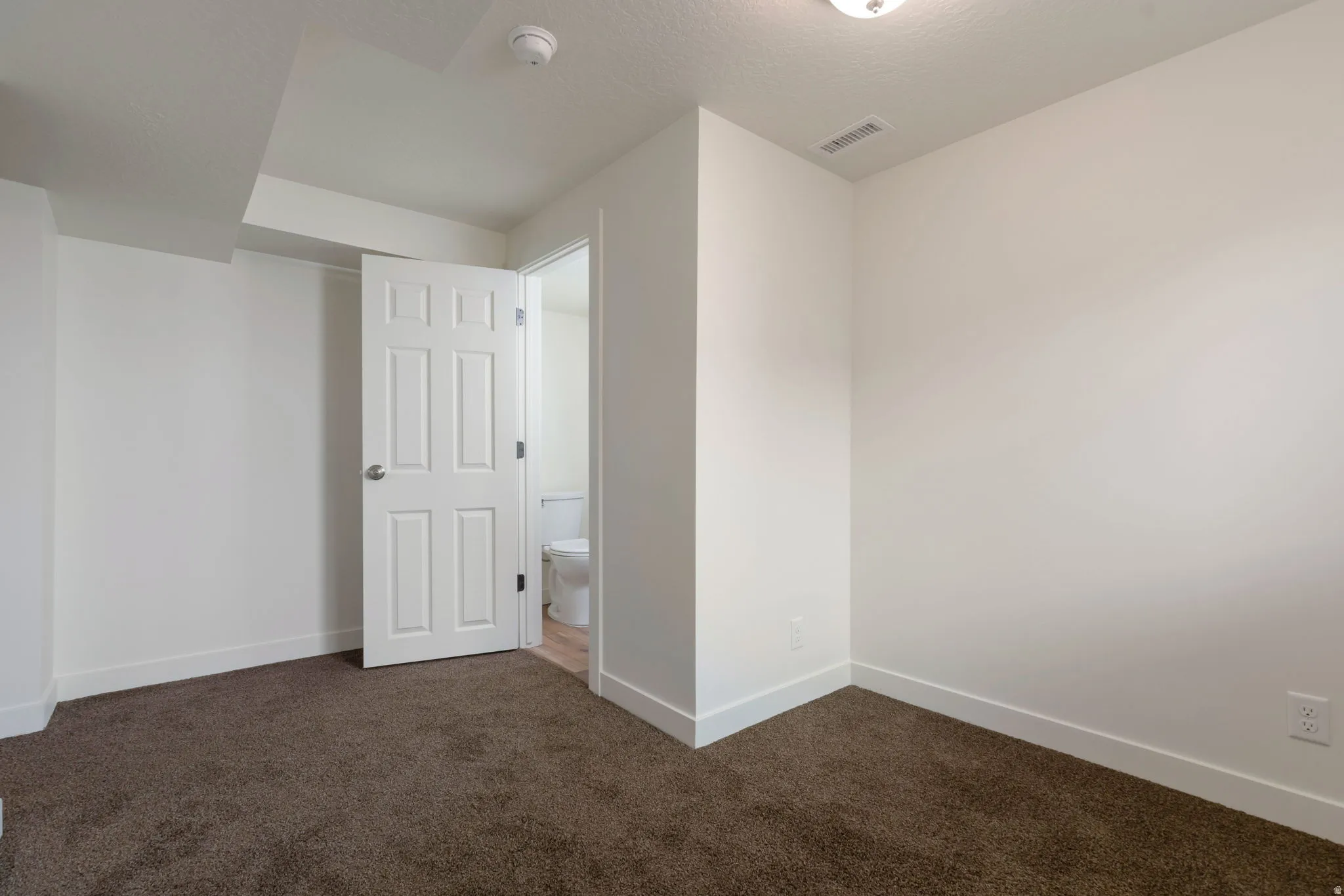 Unfurnished bedroom with dark carpet and a textured ceiling