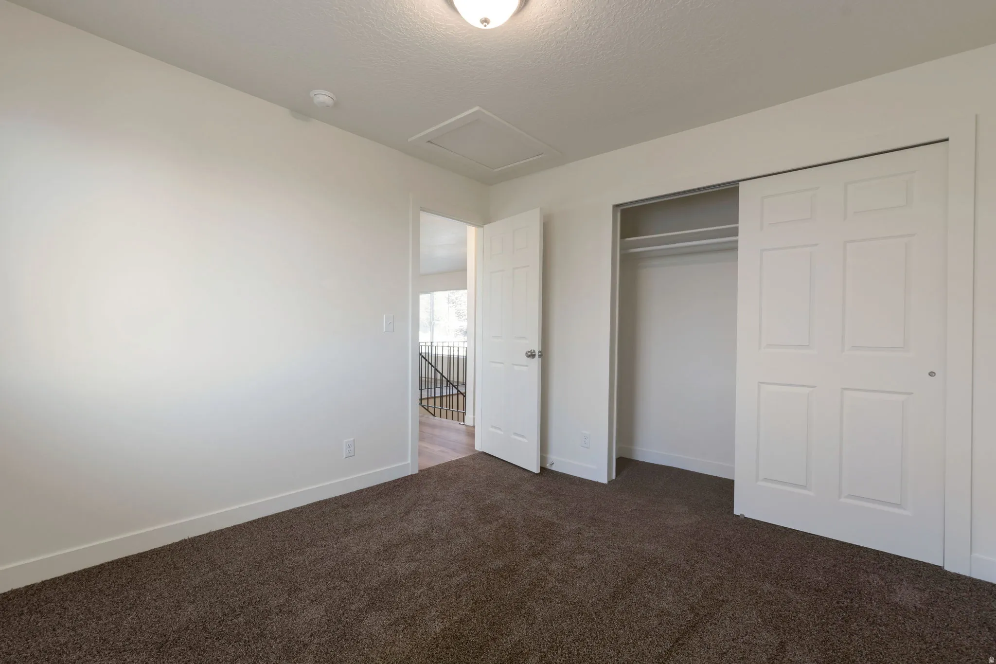 Unfurnished bedroom featuring a closet, dark colored carpet, and a textured ceiling