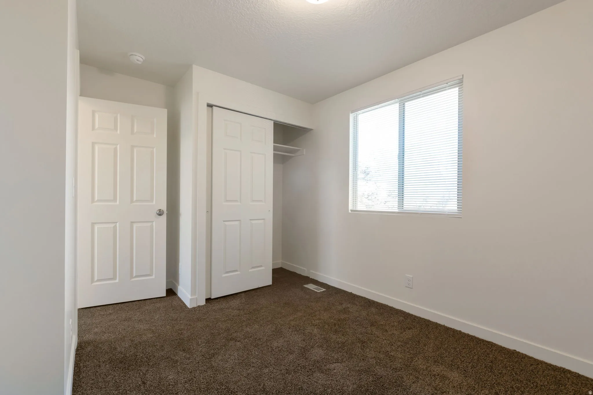 Unfurnished bedroom with dark carpet, a closet, and a textured ceiling