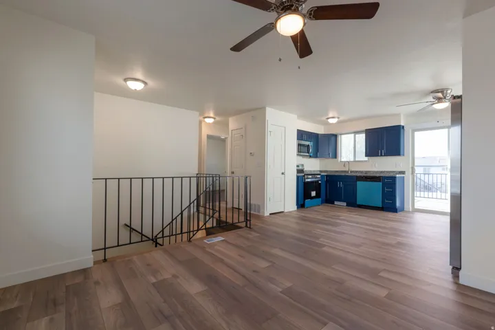 Unfurnished living room featuring dark wood-type flooring and a ceiling fan