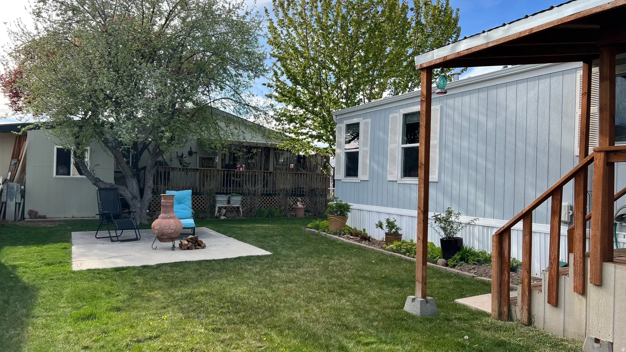 View of green lawn with a patio and a wooden deck