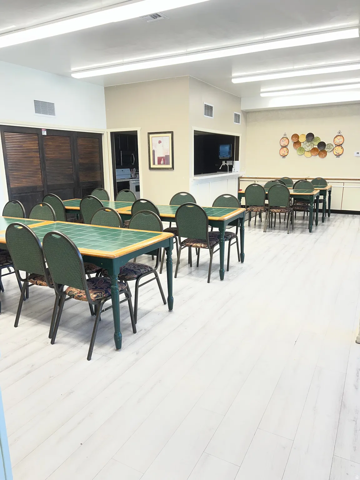 Spacious communal area featuring light wood-finish flooring, recessed lighting, and a service counter with pass-through