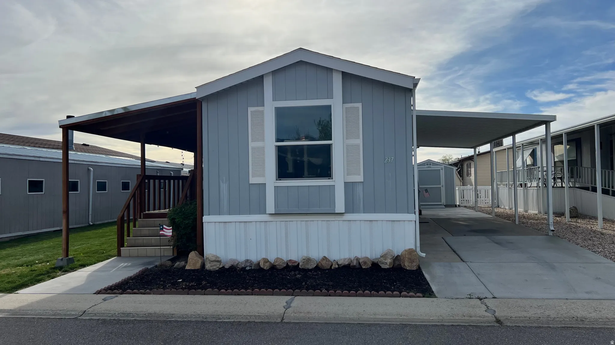 View of front of house featuring a carport, driveway, a storage shed, and a porch