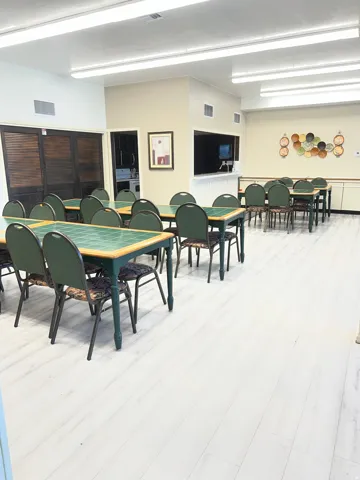 Spacious communal area featuring light wood-finish flooring, recessed lighting, and a service counter with pass-through