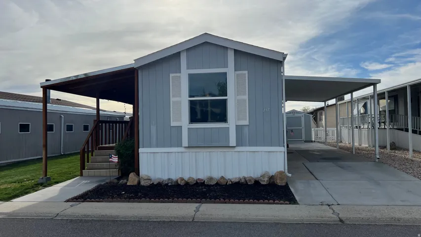 View of front of house featuring a carport, driveway, a storage shed, and a porch